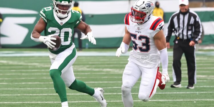 A New York Giants player, number 20, runs with the football while a New England Patriots player, number 53, pursues.