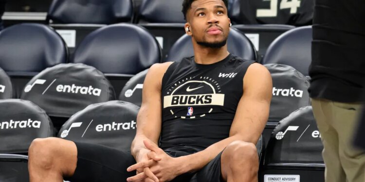 Giannis Antetokounmpo watching the warmup session from the bench.