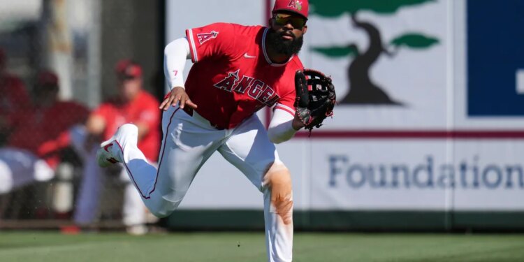 Jo Adell, wearing an Angels uniform, lunges to catch a baseball.