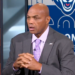 Charles Barkley speaking with his hands clasped together, wearing a gray suit and purple patterned tie.