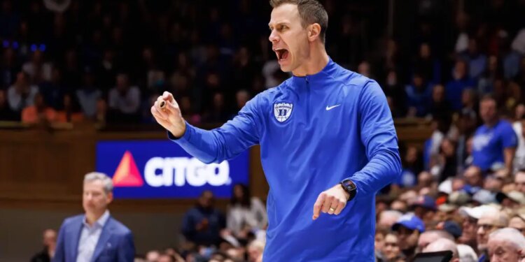 Duke head coach Jon Scheyer shouts towards the court during a college basketball game.