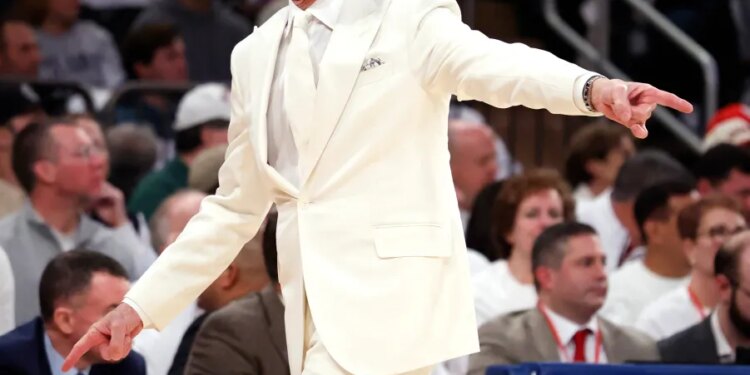 St. John's head coach Rick Pitino in a white suit, shouting and pointing during a game against Villanova.