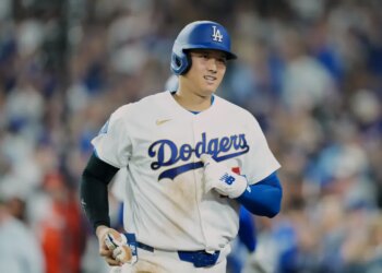 Shohei Ohtani in a Los Angeles Dodgers uniform and helmet on the field.