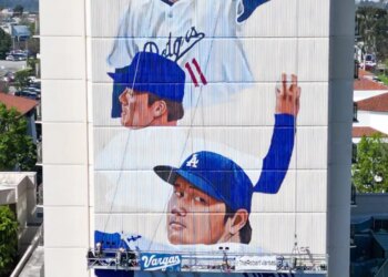 Mural of two Dodgers players on a building, with two workers on a platform painting below.