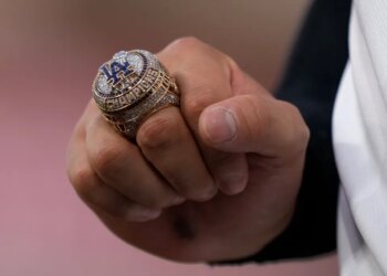 A close-up of Shohei Ohtani's hand holding a Los Angeles Dodgers World Series ring.