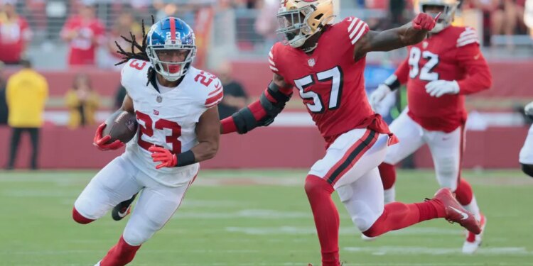 Gary Brightwell of the New York Giants runs the ball as Dre Greenlaw of the San Francisco 49ers gives chase.