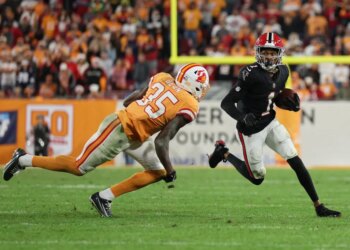 A Tampa Bay Buccaneers defender attempts to tackle an Atlanta Falcons player carrying the football.