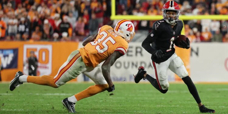 A Tampa Bay Buccaneers defender attempts to tackle an Atlanta Falcons player carrying the football.