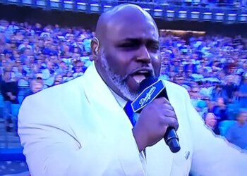 Gospel singer Keith Williams Jr. singing the national anthem with a microphone that has "Dodgers" written on it.