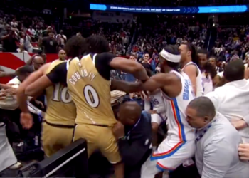 Basketball players in gold and white uniforms involved in a scuffle on the court.