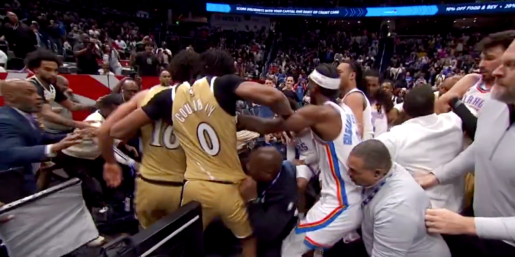 Basketball players in gold and white uniforms involved in a scuffle on the court.