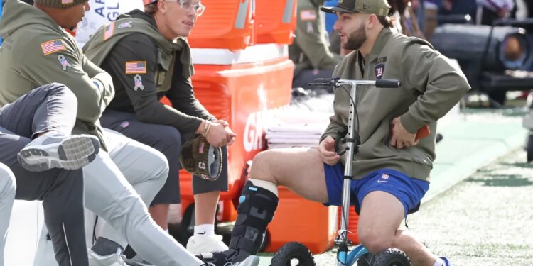 New York Giants quarterback Jaxson Dart and running back Cam Skattebo chat before a game.