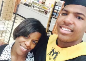 A smiling woman and a young man in a graduation cap and gown with a gold stole featuring a black "M" logo.