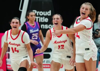 Three elated basketball players in "Mustangs" jerseys celebrating on the court.