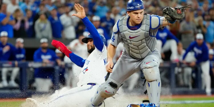 Blue Jays runner Isiah Kiner-Falefa sliding into home plate as Dodgers catcher Will Smith reaches for the ball.