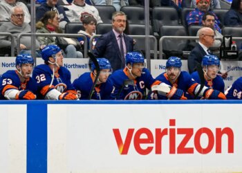 New York Islanders head coach Patrick Roy observes from the bench as players watch the game.