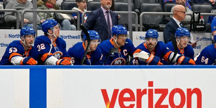 New York Islanders head coach Patrick Roy observes from the bench as players watch the game.