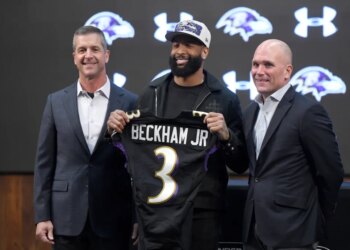 Odell Beckham Jr. holds up a Ravens jersey with head coach John Harbaugh and general manager Eric DeCosta at a news conference.