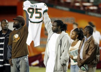 Bryan Pata's family holds up his jersey at the beginning of an NCAA college football game between Miami and Boston College.