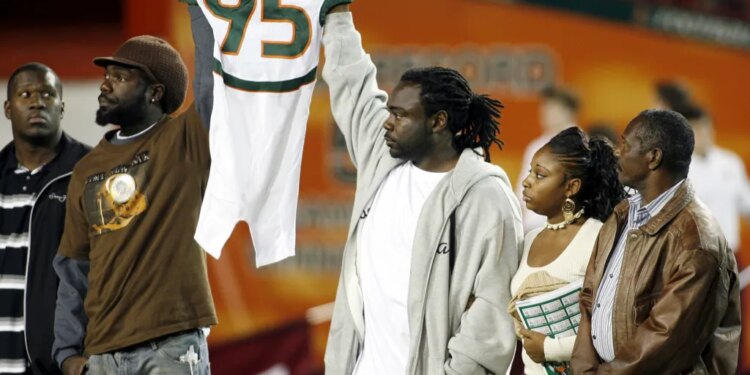 Bryan Pata's family holds up his jersey at the beginning of an NCAA college football game between Miami and Boston College.
