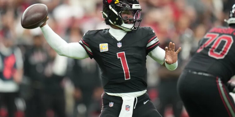 Kyler Murray in a black uniform with a red number 1, throwing a football.
