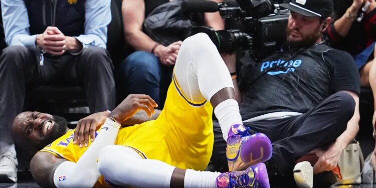 LeBron James grimaces in pain after falling while going up for a basket past Nikola Jokić during the fourth quarter of the Lakers' 120-113 loss to the Nuggets in Denver on March 5, 2026.