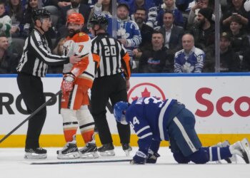 Anaheim Ducks defenseman Radko Gudas (7) looks at injured Toronto Maple Leafs forward Auston Matthews (34) after a knee-on-knee hit, as two referees stand between them.