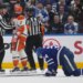 Anaheim Ducks defenseman Radko Gudas (7) looks at injured Toronto Maple Leafs forward Auston Matthews (34) after a knee-on-knee hit, as two referees stand between them.