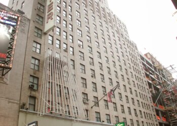 The Hotel Carter building and its entrance marquee from an upward angle, with a taxi driving by.