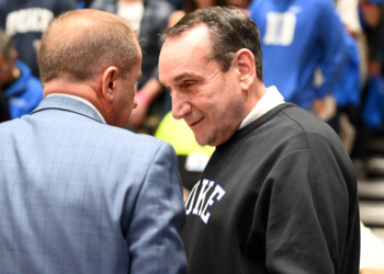 Duke Blue Devils former head coach Mike Krzyzewski chatting with someone in a light blue plaid suit.