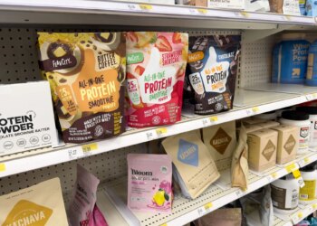 Photo of a protein aisle at Target showing an All-in-one protein smoothie in a butter coffee flavor, as well as strawberry shortcake and chocolate, among several other protein powders.