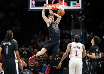 Brooklyn Nets' Grant Nelson slams the ball as Cleveland Cavaliers' James Harden watches.