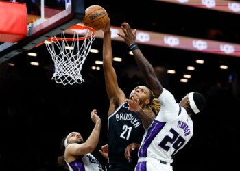 Brooklyn Nets player Noah Clowney (21) shooting over Sacramento Kings players Devin Carter (22) and Daeqwon Plowden (29).