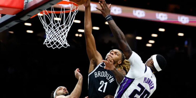 Brooklyn Nets player Noah Clowney (21) shooting over Sacramento Kings players Devin Carter (22) and Daeqwon Plowden (29).