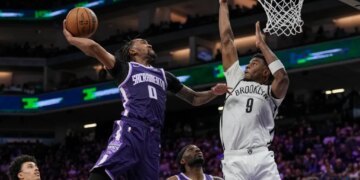Malik Monk attempts a dunk for the Sacramento Kings while E.J. Liddell of the Brooklyn Nets defends.