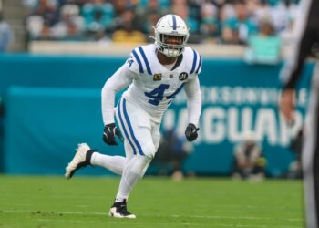A football player in a white uniform with blue stripes and the number 44 running on a green field.