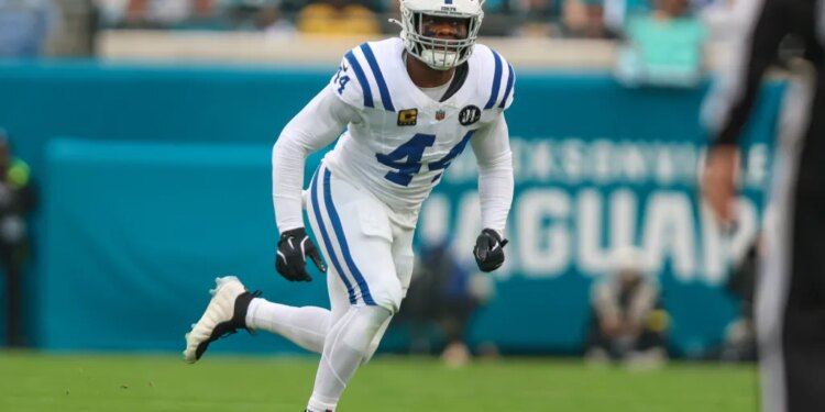 A football player in a white uniform with blue stripes and the number 44 running on a green field.