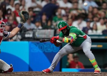 Randy Arozarena batting, with a catcher behind him and a baseball in the air.