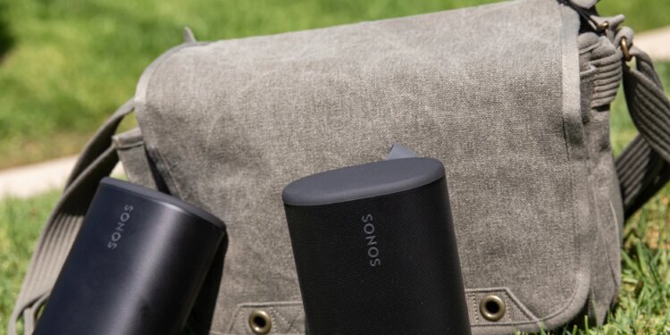 Two Sonos Play speakers in front of a sage colored bag on the grass.