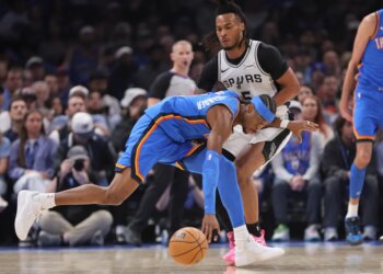 Oklahoma City Thunder guard Shai Gilgeous-Alexander, center, tries to keep control of the ball against San Antonio Spurs guard Stephon Castle (5).