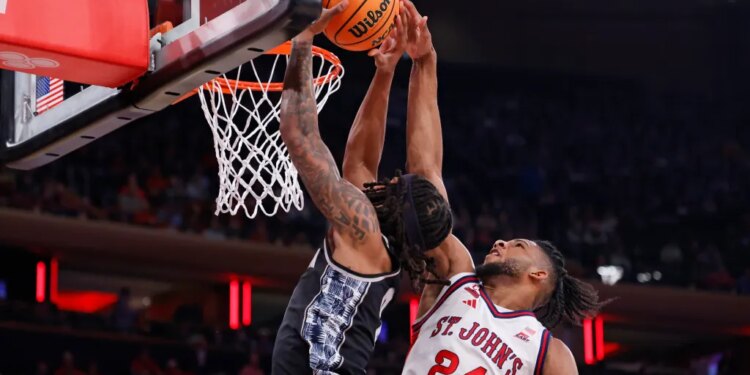 Zuby Ejiofor #24 of the St. John's Red Storm jumps to defend a shot by a Georgetown Hoyas player.
