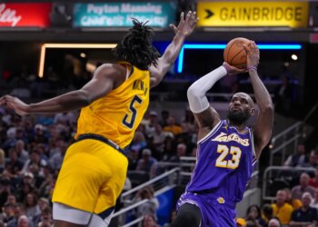 LeBron James in a purple Lakers jersey shoots a basketball while Jarace Walker in a yellow Pacers jersey defends.