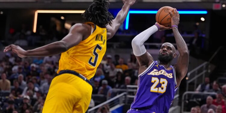 LeBron James in a purple Lakers jersey shoots a basketball while Jarace Walker in a yellow Pacers jersey defends.
