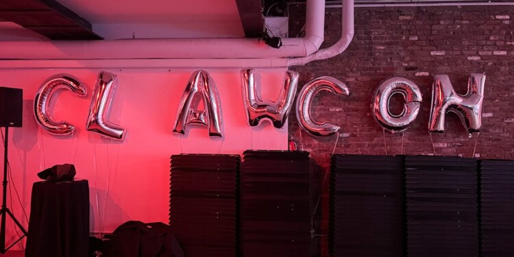 An image of a room with pink lighting and silver balloons spelling out CLAWCON.