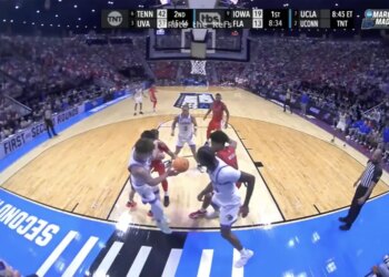 Basketball players in white and red jerseys on a court during a March Madness game.
