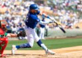 Los Angeles Dodgers infielder Miguel Rojas hits a baseball during a spring training game.