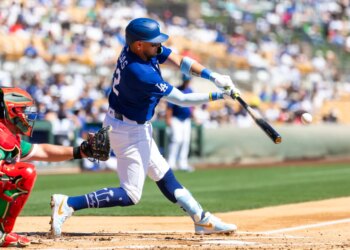 Los Angeles Dodgers infielder Miguel Rojas hits a baseball during a spring training game.