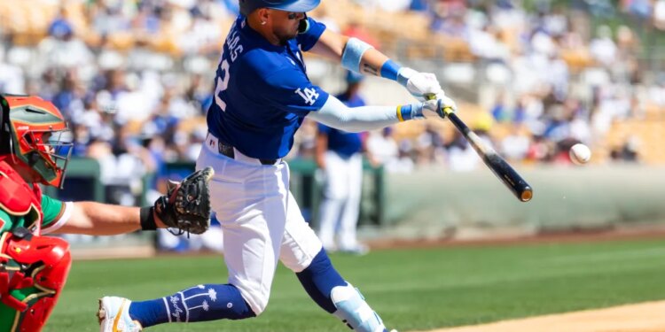 Los Angeles Dodgers infielder Miguel Rojas hits a baseball during a spring training game.