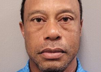 Golfer Tiger Woods stands next to his overturned vehicle.