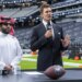 Turki Alalshikh and Tom Brady at a podium with a football in a stadium.